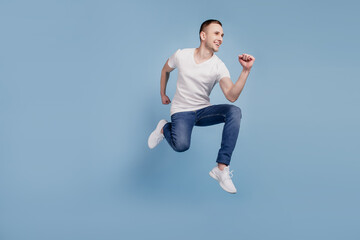 Full length profile side photo of excited young guy attractive man jumping running isolated over blue color background