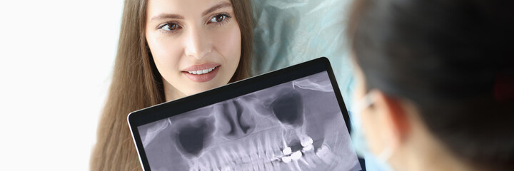 Dentist doctor holding digital tablet with teeth xray in front of patient