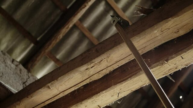 A farmer hangs a scythe on the beam of an old brick barn