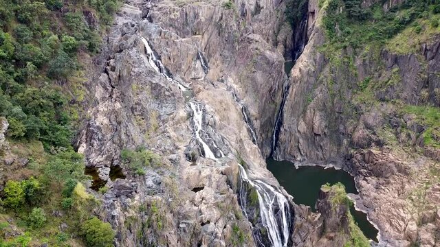 Aerial - drone shot of multiple waterfalls cascading down rocky mountainside, Queensland