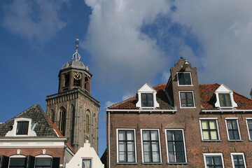 Fototapeta na wymiar The facades of beautiful old buildings and the tower of the Great Church in the city of Deventer, The Netherlands