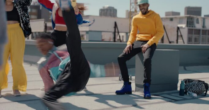 man breakdancing on rooftop at hip hop dance party performing crazy breakdance moves with friends dancing and celebrating 