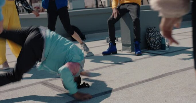 man breakdancing on rooftop at hip hop dance party performing crazy breakdance moves with friends dancing and celebrating 