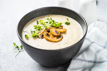 Mushroom Soup in black bowl on light stone table.