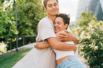 Fototapeta premium Young multiethnic friends hugging outdoors cuddling affectionate and bonding
