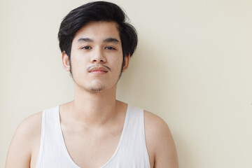 Asian wearing a gray sweater handsome young man smiling indoors with yellow background concept.  
