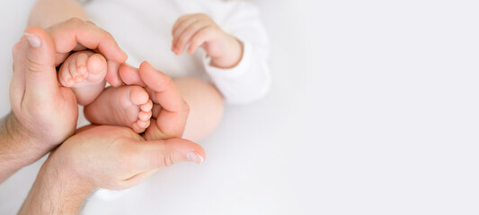 Small newborn baby legs in the shape of a heart in dad's strong male hands. Tenderness and love from birth. Care and raising of children health. banner - obrazy, fototapety, plakaty