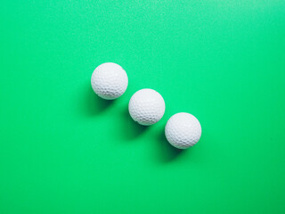 Top view of golf ball on green background.