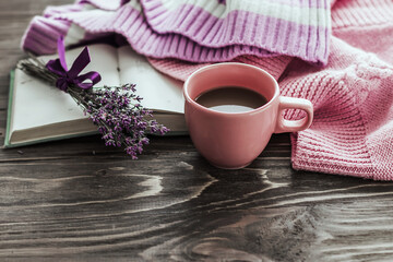 Obraz na płótnie Canvas A cup of coffee on a wooden table, an open book and a warm sweater on the background of a bouquet of lavender flowers. Still life concept. Cozy morning.