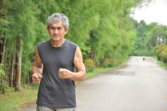 An Old Man Running Along  The Road Among The Nature Atmosphere, When Coronavirus Or Covid-19 Is Spreading To Stay Away From People To Be Safe From Covid-19 Infection