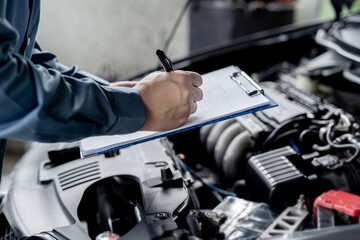 Close up hand car service staff check engine malfunctions and mistake check list in engine room : Car service concept