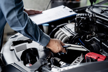 Technician hold and check the engine air filter in engine room and check list service work in the garage  : Car service concept