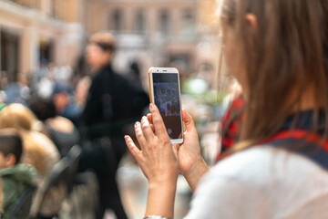 Woman taking pictures using smartphone or filming video of models on catwalk