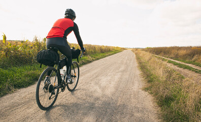 Obraz premium Bike traveler riding through the field on bicycle with bags
