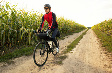Bike traveler riding through the field on bicycle with bags