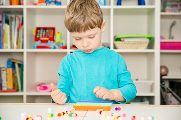 Fototapeta premium Child plays with sensory fidget toy Pop-it. Instrument for fine motoric skils, tool to start counting, learn primary arithmetic operations. A sedative for finger stimulation, relaxation.