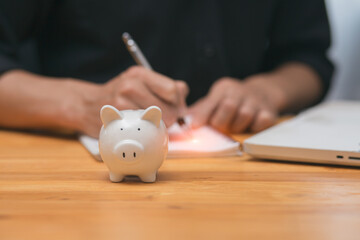 Obraz na płótnie Canvas Businessman holding a bright pig piggy bank a coins on wooden table 