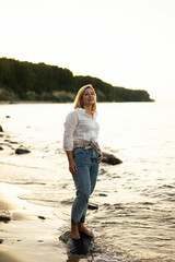 Portrait of middle aged woman standing at the beach at sunset