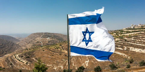 Israeli flag on the background of Judea and Samaria. Sunny day overlooking rare settlements in the...