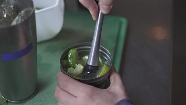 Close up shot of Bartender making Cynar Drink with lime and smashing with mortar