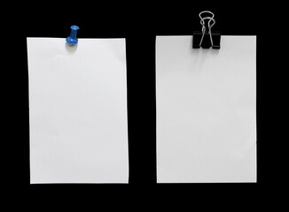Blank paper with pin and clip on black background.
