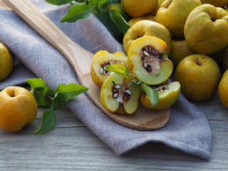 Ripe yellow fruit of the shrub Chaenomeles japonica with a wooden spoon on a wooden background, top view. Seasonal autumn quince crop with vitamin C and sour taste. Gardening and cultivation 