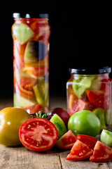 Canned tomatoes on a glass jar and black background, close up look