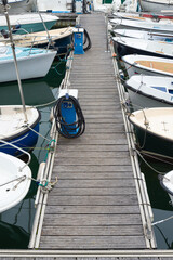 Several boats moored at both sides of a wooden gangway, vertical photo, Santander jetty, Spain.