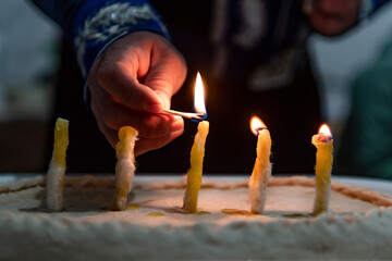 Kalmykian New Year Zul a man lighting handmade candles from wool and butter on a tight dough pie