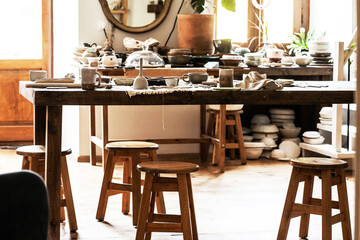 interior with table stools and a mirror in a ceramic studio, daylight, side view, general plan