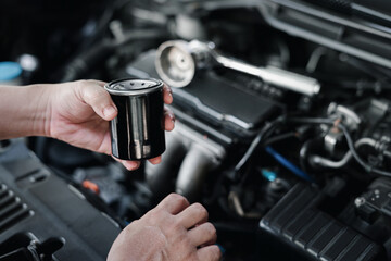 New Oil filter in hand a man and wrench in the gasoline engine compartment : service concept of car