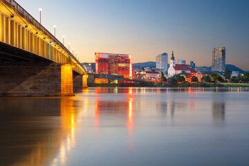 Linz, Austria. Cityscape image of riverside Linz, Austria at summer sunset with reflection of the city lights in Danube river.