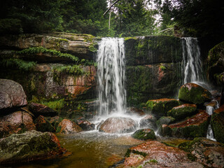 Obraz premium Amazing waterfall hidden deep in Jizera mountains, Czech Republic. Calm and peaceful place with water flowing in cascade river.