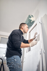 Young adult man painting on a DIY budget renovation of his new home apartment.