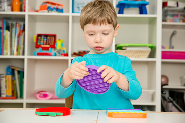 Child plays with sensory fidget toy Pop-it. Instrument for fine motoric skils, tool to start counting, learn primary arithmetic operations. A sedative for finger stimulation, relaxation.