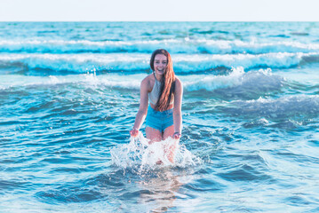 Young woman playing in the sea.woman make in sea water splash.Cheerful young woman having fun on the summer beach.