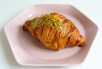 delicious french croissant with pistachios on a pink plate