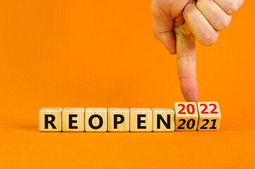 2022 reopen new year symbol. Businessman turns wooden cubes and changes words 'Reopen 2021' to...