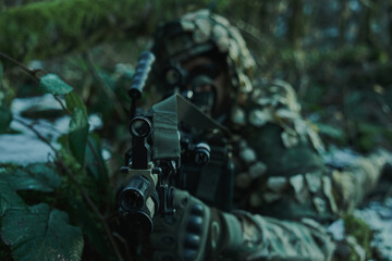 Portrait of airsoft player in professional equipment in helmet aiming at victim with gun in the...