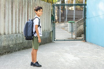 Child with his backpack ready to enter the school for the beginning of classes. He turns and greets...