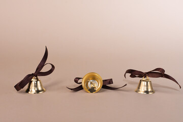 golden bells on a beige background close-up, with bows made of brown ribbons. copy space