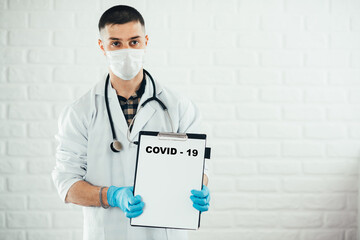 A doctor with a tablet on a white background shows the name of the disease with a pen covid-19