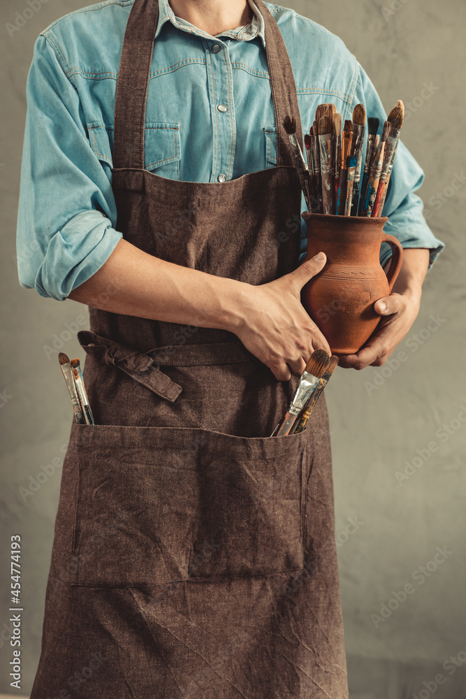 Poster man artist painter holding clay jug with paint brush. painter artist and paintbrush in studio