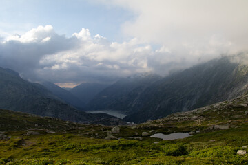 Naklejka premium Amazing Landscape in the hearth of Canton Bernese in Switzerland. Drive on the Grimselpass. Epic scenery with the clouds and fog. Wonderful sun rays through the clouds and later an amazing sunset.