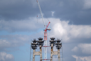 Tall construction crane against the blue sky. Tower crane for lifting loads in the construction of...