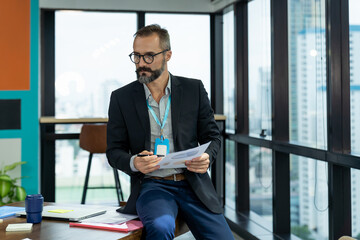 Naklejka na ściany i meble Portrait of confident businessman in suit and wearing glasses working in the modern office. business and office concept