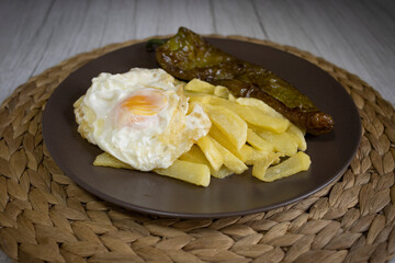 Fried potatoes with fried egg and fried pepper, a highly demanded food in southern Spain. The potatoes should not be frozen, and all homemade. Made all with olive oil. Front view