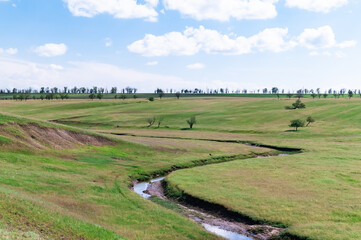 A winding stream flows through the steppe and goes behind the hill