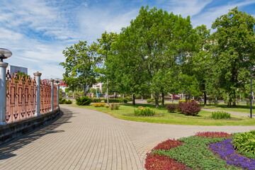 Obraz premium Green city park with walking paths, trees and flower beds