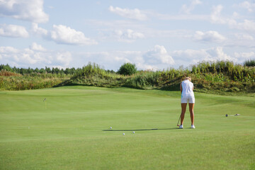 Beautiful tanned golfer girl on the golf course.